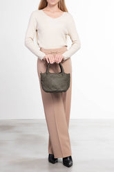 Donna che tiene La Nora mini borsa a mano in pelle intrecciata verde vista frontale