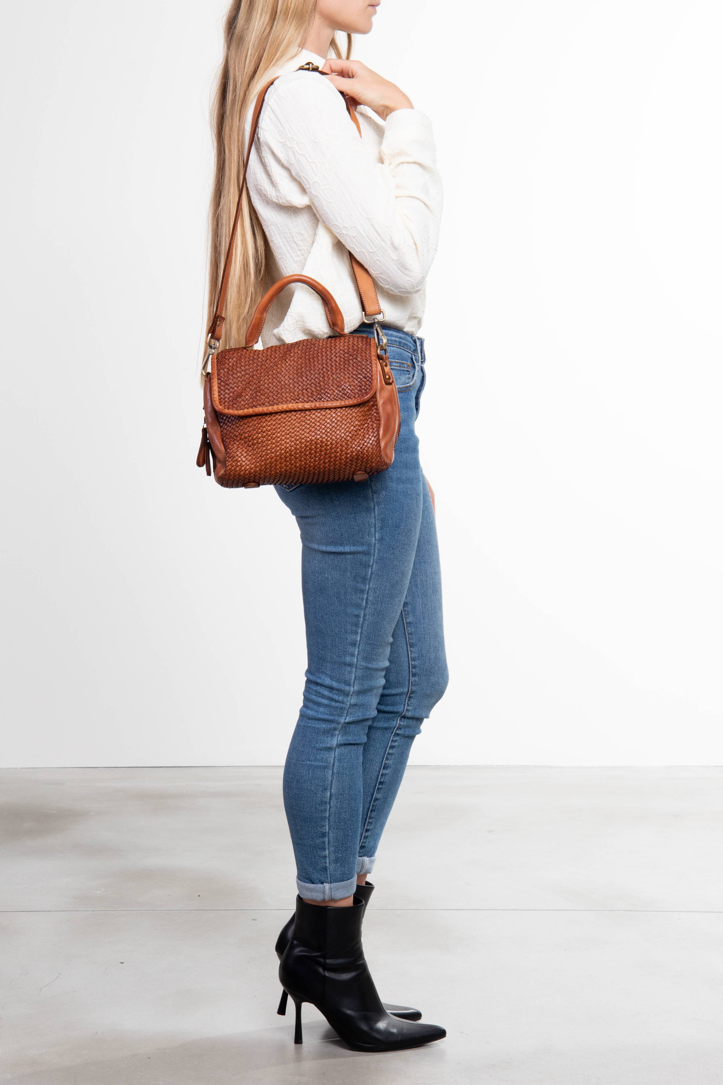 Donna che indossa una borsa a mano in pelle intrecciata colore cuoio sulla spalla