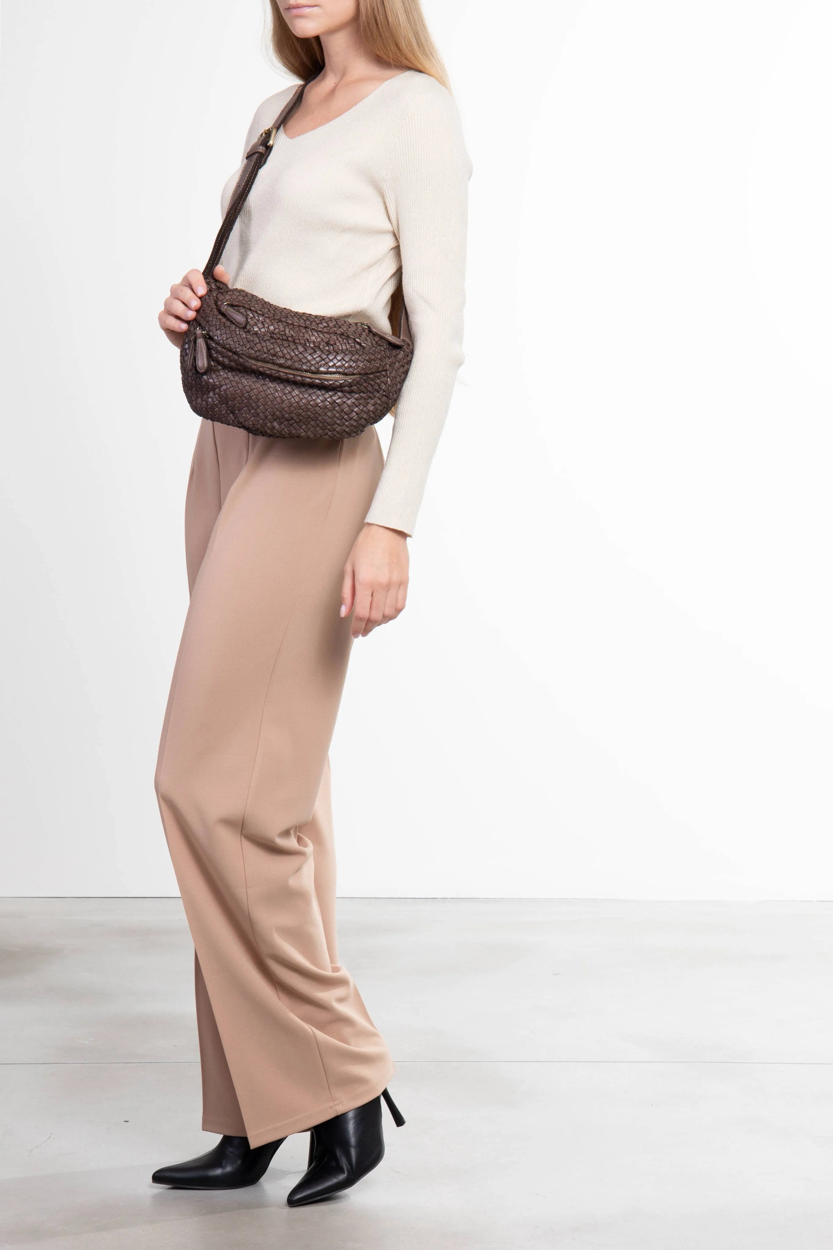 Borsa a tracolla in pelle intrecciata color taupe indossata da donna vista laterale