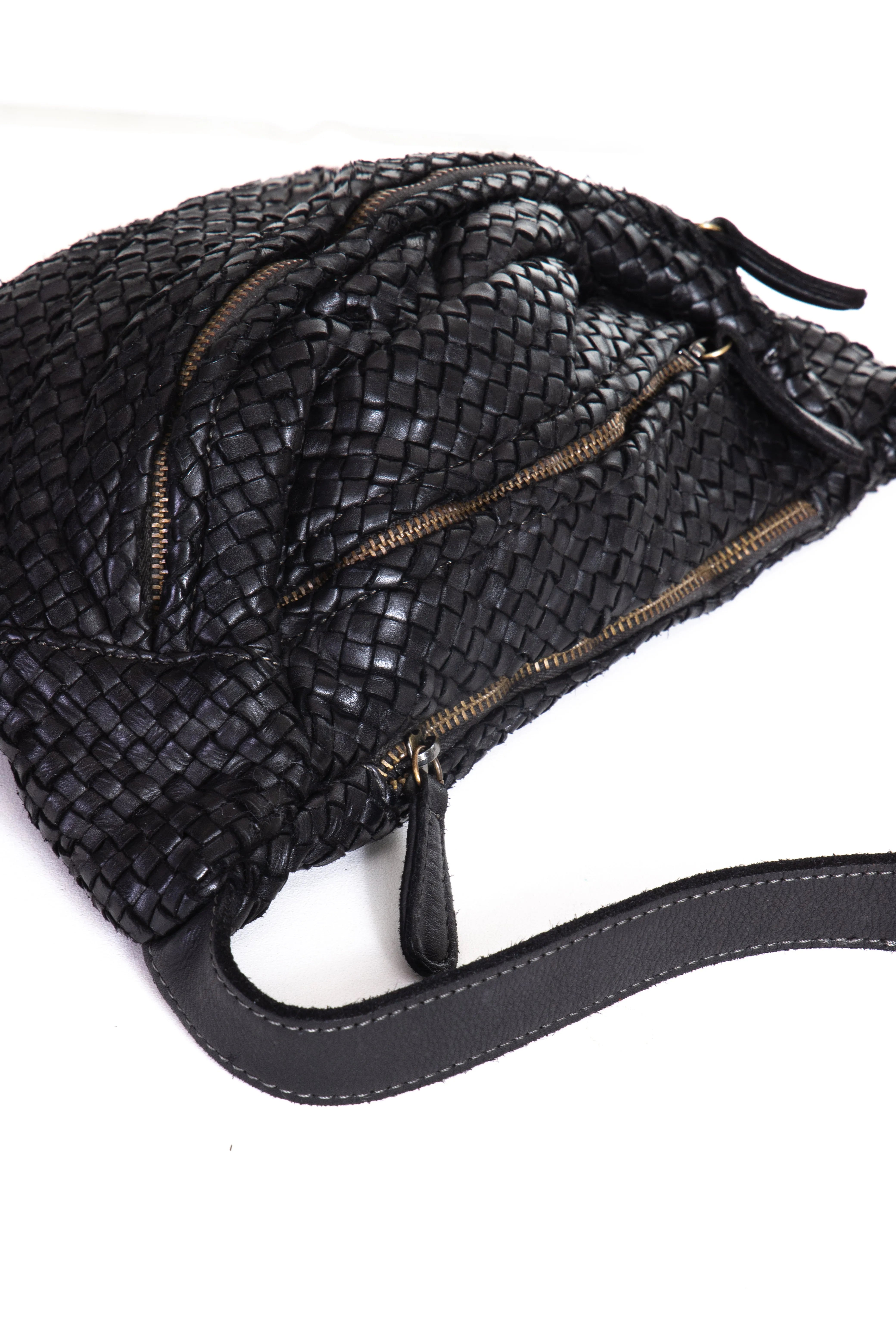 Woven leather crossbody bag in black color laid down showing zipper
