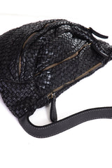 Woven leather crossbody bag in black color laid down showing zipper

