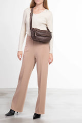 Borsa a tracolla in pelle intrecciata color taupe indossata da donna vista frontale
