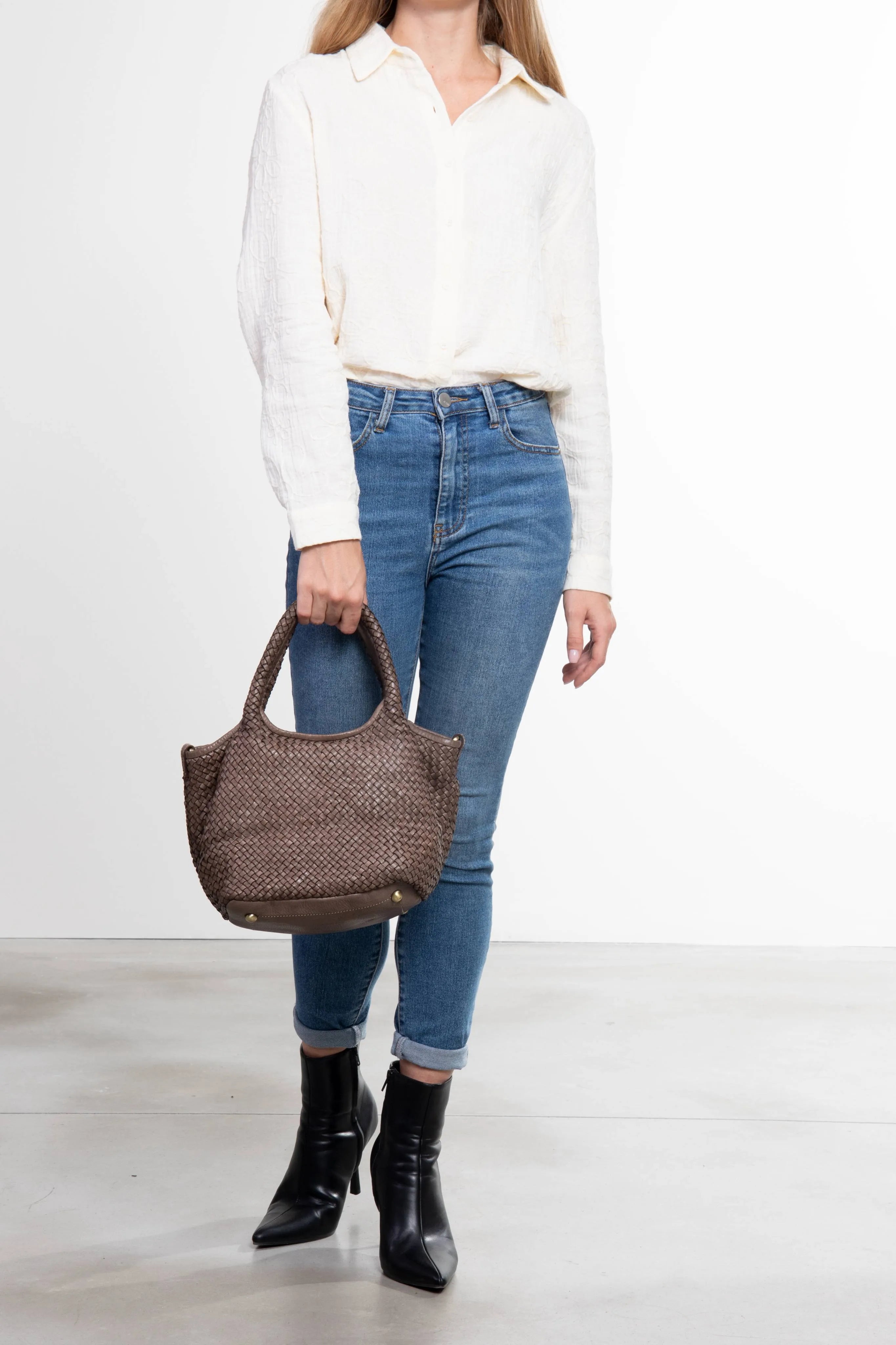Donna che tiene la borsa tote Tuscan Weave in pelle intrecciata colore taupe vista frontale