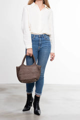 Donna che tiene la borsa tote Tuscan Weave in pelle intrecciata colore taupe vista frontale